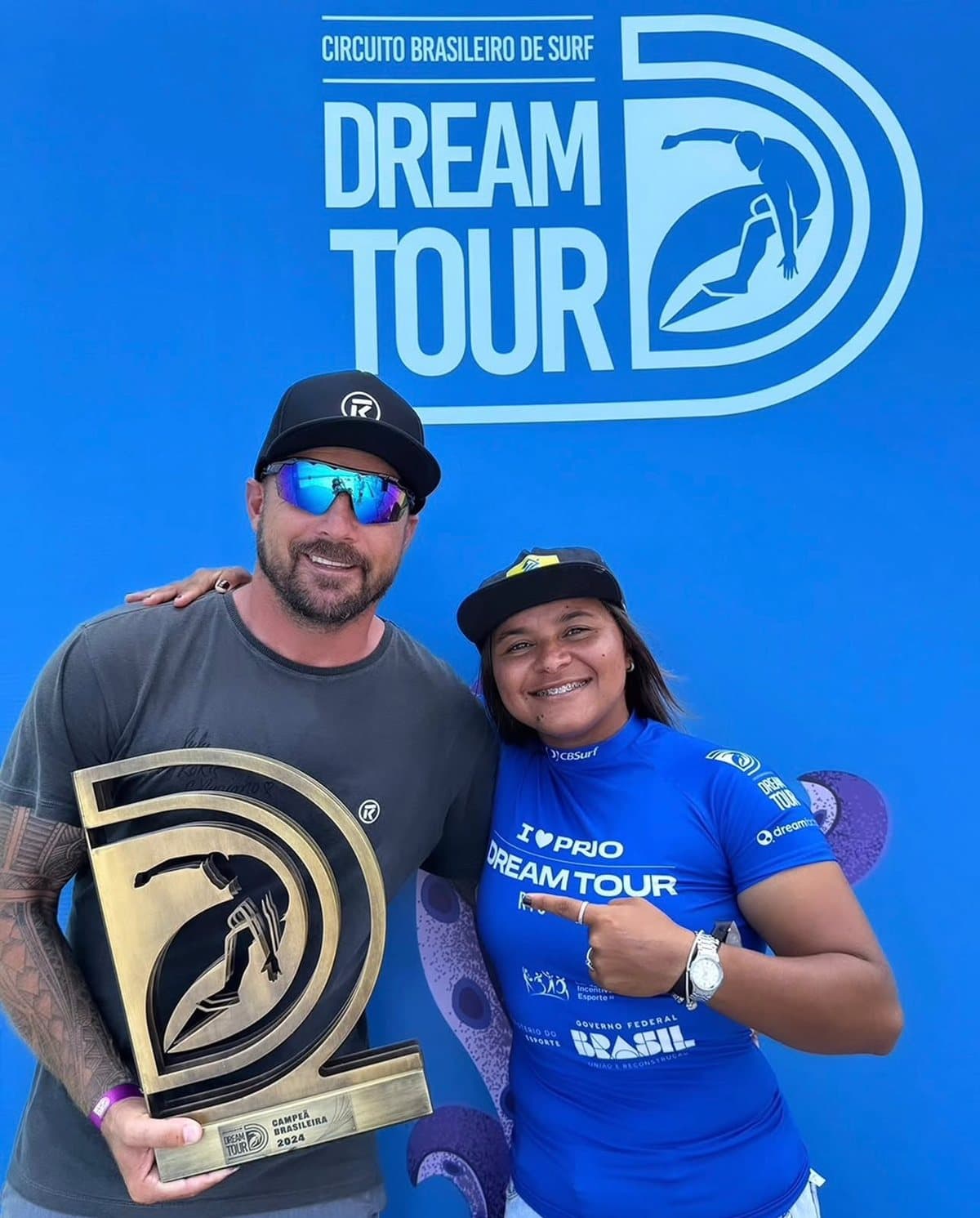 Coach Kokinho com a atleta Juliana dos Santos, campeã do Dream Tour 2024, segurando o troféu